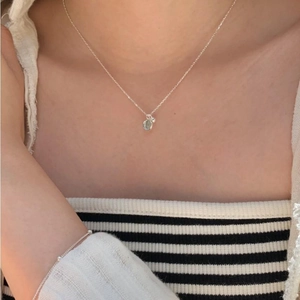 Macro detail of a 925 sterling silver chain featuring a tiny light blue crystal pendant
