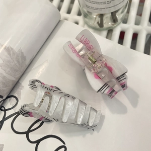Detail showing acrylic hair claw clips with pink lettering and marble pattern