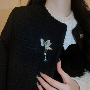 Close-up of butterfly brooch with zircon tassels pinned on a black tweed jacket