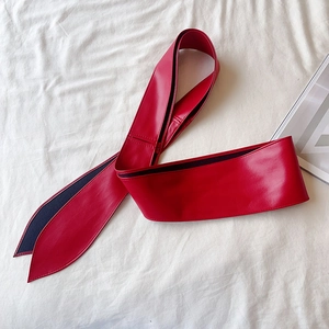 Vue à plat d'une large ceinture corset en similicuir rouge avec fermeture à nouer chic