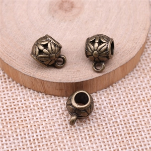 Antique bronze hollow floral metal beads for DIY jewelry making on wooden background