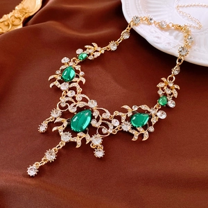 Macro detail of vintage gold necklace with green teardrop gemstones and crystals