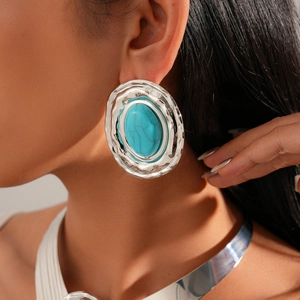 Close-up of oversized oval silver earrings with blue stones on model for fashion look