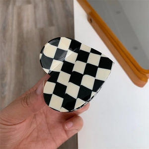 Detail of a heart-shaped claw clip featuring a classic black and white checkered pattern
