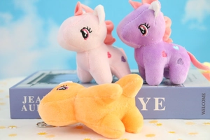 Close-up of pink, purple and orange plush unicorn keychains with heart embroidery
