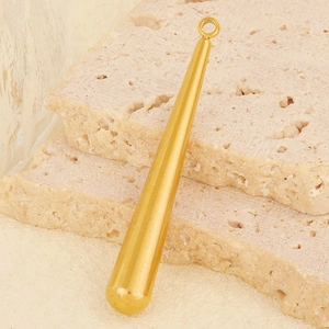 Macro view of golden teardrop pendant with mirror finish on natural stone background