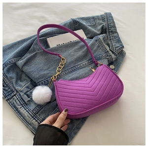 Detalle del bolso de fieltro morado con acolchado en V y un pompón de piel blanca