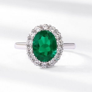 Oval emerald green lab-grown gemstone ring with silver halo diamond setting