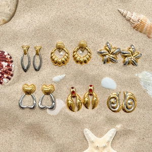 Vue à plat de boucles d'oreilles vintage or et argent avec perles sur fond de sable