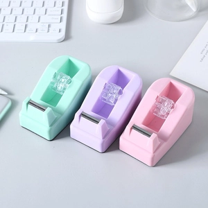 Minimalist macaron-colored tape dispensers in mint, purple, and pink on a white desk