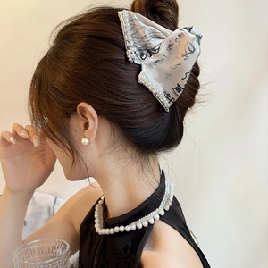Detail of elegant bow hair claw clip with ink pattern fabric and pearl edges on hairstyle