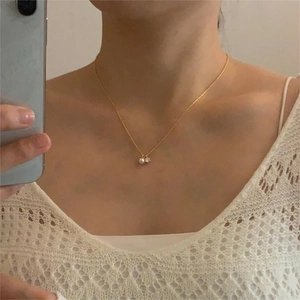 Close-up of a gold 925 silver necklace with a dainty pearl and zircon pendant on a neck