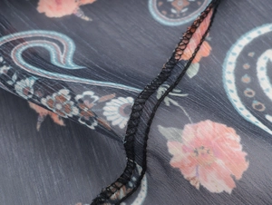 Detailed macro view of dark paisley chiffon fabric with pink and blue floral patterns
