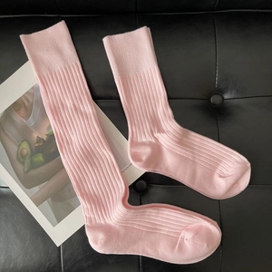 Detail shot of pink ribbed knit long socks on black leather with a fashion magazine card