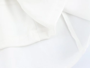 Detail shot of white fabric texture showing precision stitching and hemline quality