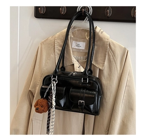 Detail of black bowling bag with gloss finish, front pockets and cute puppy pendant accessory