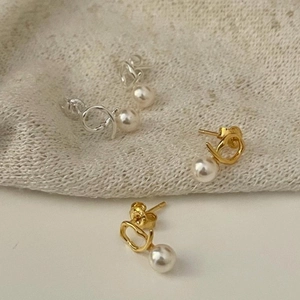 Detailed close-up of knotted sterling silver pearl earrings in gold and silver finish