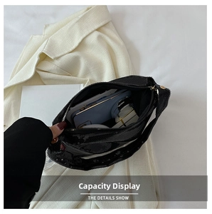 Détail de la capacité intérieure du sac à bandoulière à paillettes noires avec maquillage