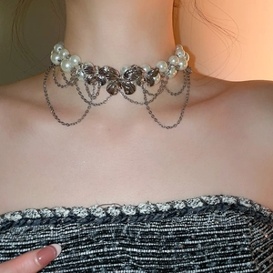 Detail of double-layer pearl choker with silver butterfly charms and delicate tassels