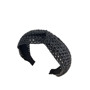 Serre-tête bohème tressé noir en paille avec nœud croisé sur fond blanc immaculé