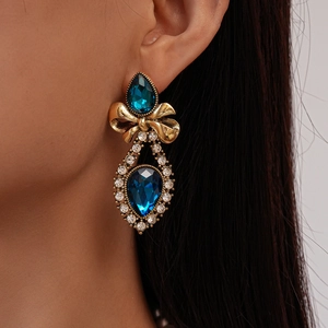 Macro shot of vintage gold bow earrings with dark blue teardrop rhinestones