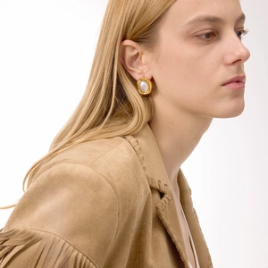 Close-up of vintage oval 18K gold plated earrings with white resin pearl on model