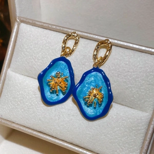 Vue macro détaillée des boucles d'oreilles émail bleu avec des accents dorés en éventail
