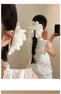 Close-up of white lace bow hair clip showing intricate floral embroidery and texture