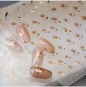 Macro detail of rose gold floral nail stickers with intricate 3D metallic rose patterns