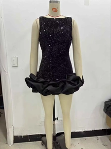 Détail de mini-robe noire à paillettes avec ourlet plissé en satin volumineux et brillant