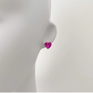 Détail macro d'une boucle d'oreille cœur en zircon rose sertie sur une monture argentée