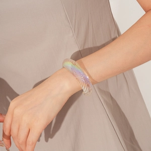 Detail of iridescent resin bracelet featuring intricate feather carved textures on wrist
