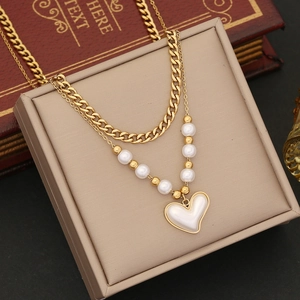 Close-up of double-layer necklace with pearl chain, gold Cuban links and heart pendant