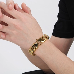 Macro view of gold chunky Cuban chain bracelet with intricate engraved textures and clasp