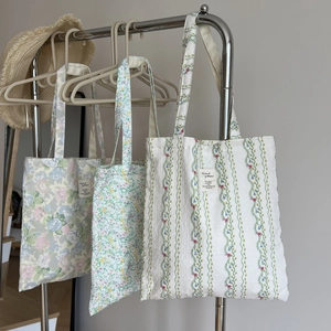 Detailed view of three floral canvas tote bags hanging on a metal rack for daily shopping
