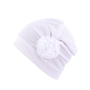 Détail d'un turban blanc pour femme avec rose en tissu faite main et texture douce
