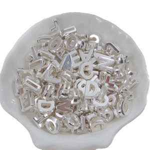 Bulk silver metallic 26 alphabet letter charms for DIY jewelry making in a white shell bowl