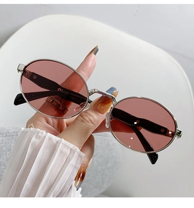 Nahaufnahme der Retro-Sonnenbrille mit silbernem Metallrahmen und rosa Gläsern in der Hand