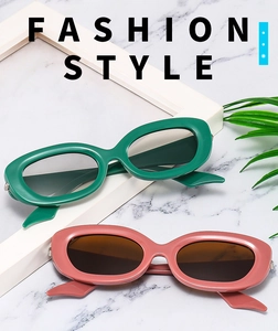 Close-up of retro oval thick-frame sunglasses in green and pink on marble background