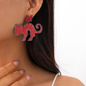 Close-up of red enamel cat earrings with dark metal edges on a professional model