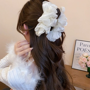 Detail of a large white mesh bow hair claw with sparkling rhinestones worn on hair