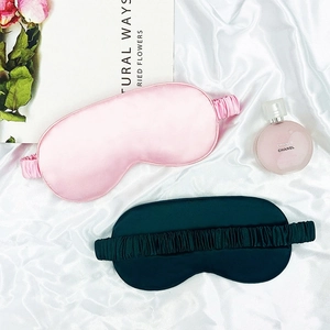 Silky pink and green sleep masks with elastic straps on elegant white silk fabric