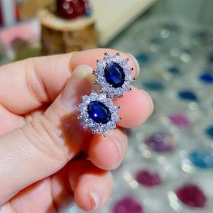 Macro shot of oval blue sapphire stud earrings with double-layered cubic zirconia halo