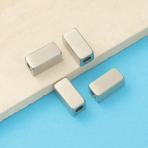Macro view of four brushed stainless steel rectangular spacer beads for jewelry DIY
