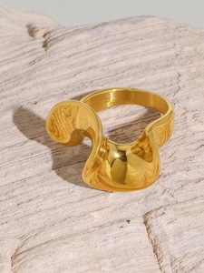 Close-up of gold-plated S-shape wavy ring on a textured stone surface with light effects