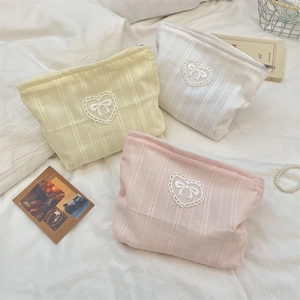 Close-up of rib-textured fabric cosmetic bags with heart lace and bow detail