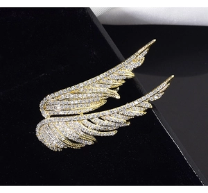 Macro shot of elegant golden angel wings brooch with sparkling rhinestones on velvet