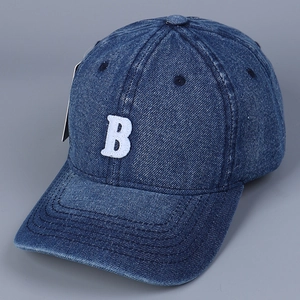 Detail of blue denim baseball cap featuring white towel embroidered letter B and texture