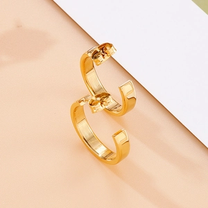 Detail of minimalist gold C-shaped stainless steel earrings with a high-polished finish