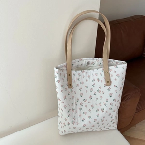 Détail du sac cabas floral en lin avec anses en cuir et fermeture à bouton pression